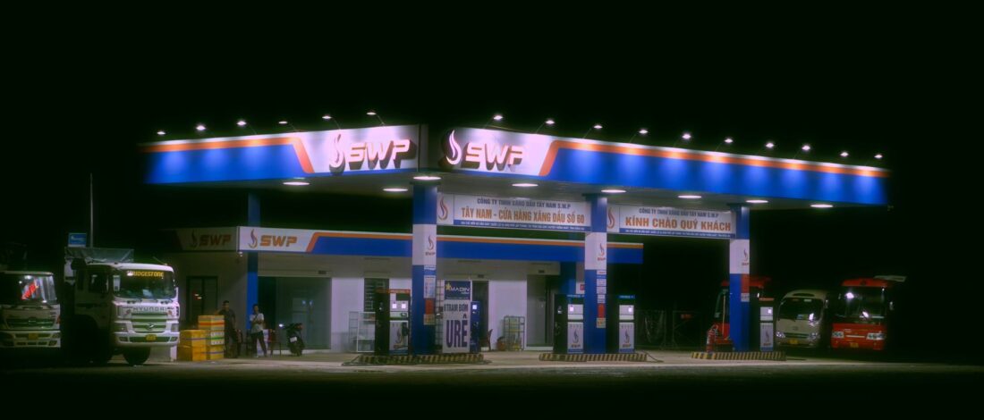Nighttime view of a brightly lit gas station with trucks and cars parked.