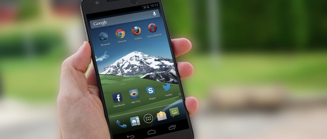 Close-up of a smartphone in hand displaying social media apps on screen.