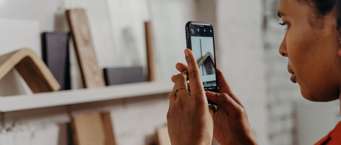 A woman uses her smartphone to photograph a model in a modern design studio.