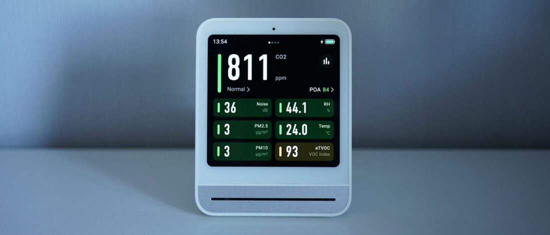 Close-up of a digital air quality monitor showing CO2 and PM2.5 levels indoors.