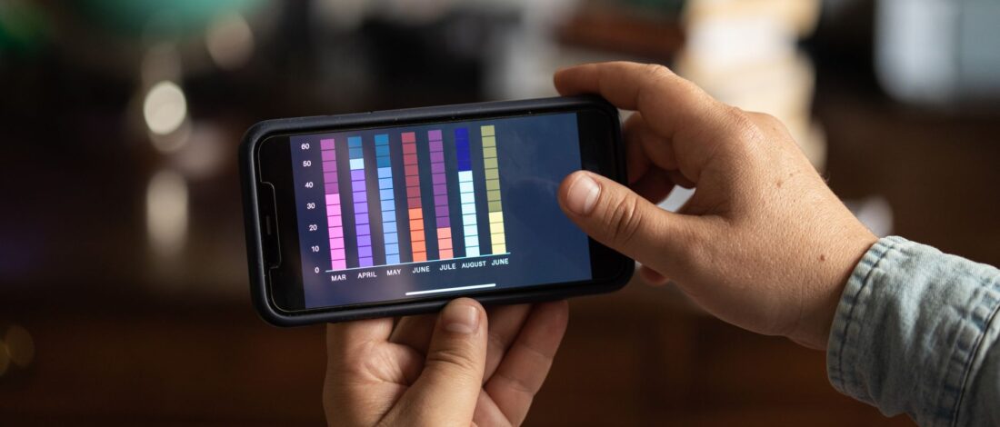 Close-up of hands holding a smartphone displaying a colorful bar graph. Perfect for business and technology themes.