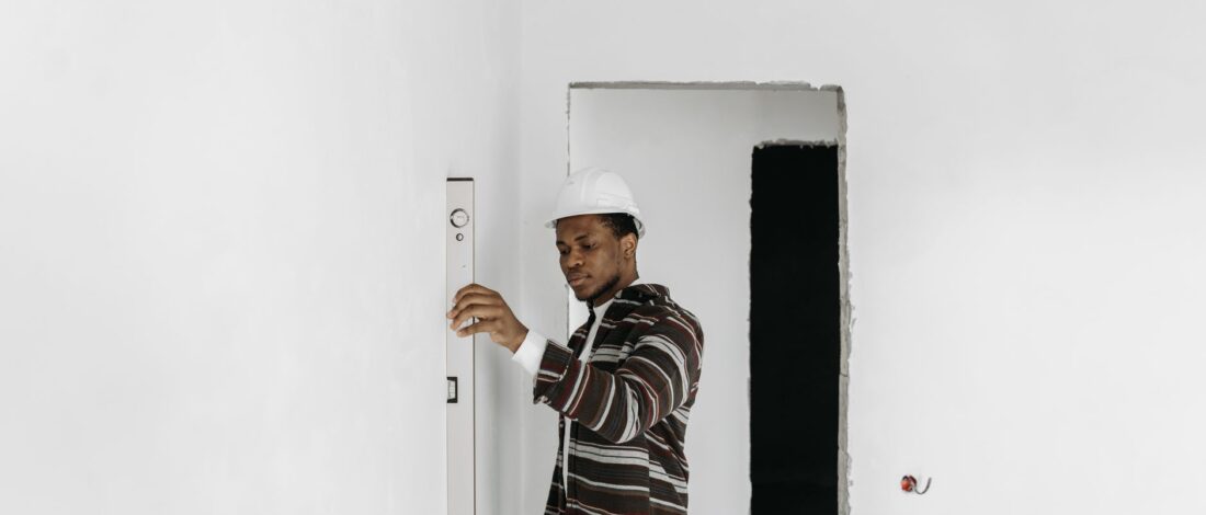 Architect wearing hard hat checks wall alignment in a renovation project.